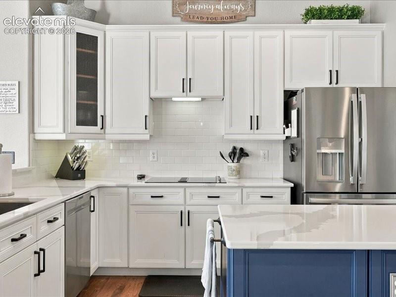 Contemporary kitchen featuring white shaker cabinetry with black hardware, white subway tile backsplash, and stainless steel appliances including a French-door refrigerator