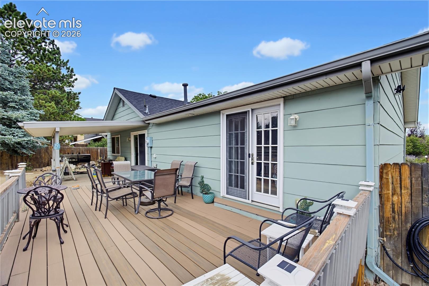 Rear exterior with a large composite deck, covered patio area, and sliding glass doors