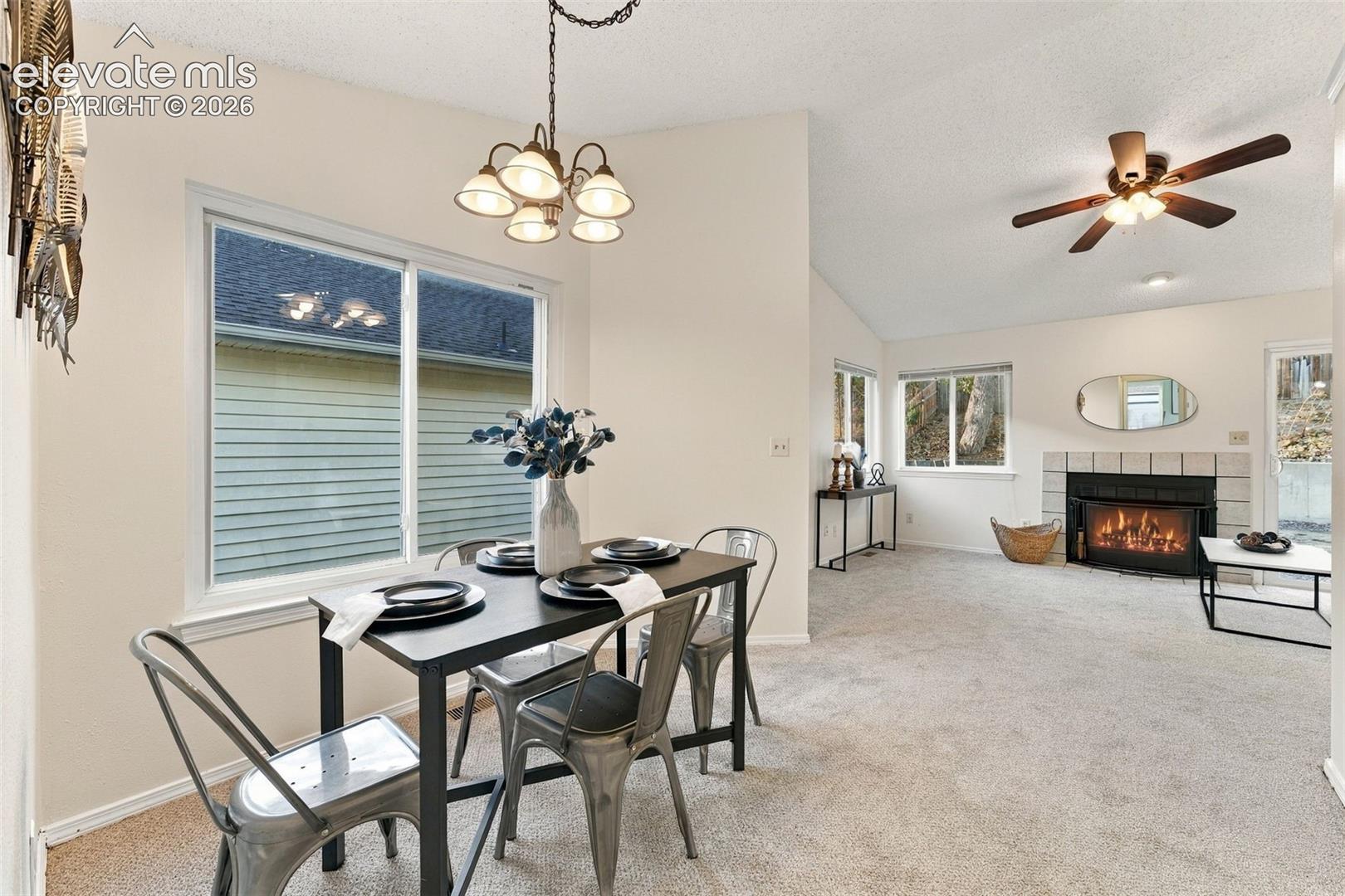 Open floor plan featuring vaulted ceilings, a fireplace with tile surround, oversized windows, and a multi-arm chandelier