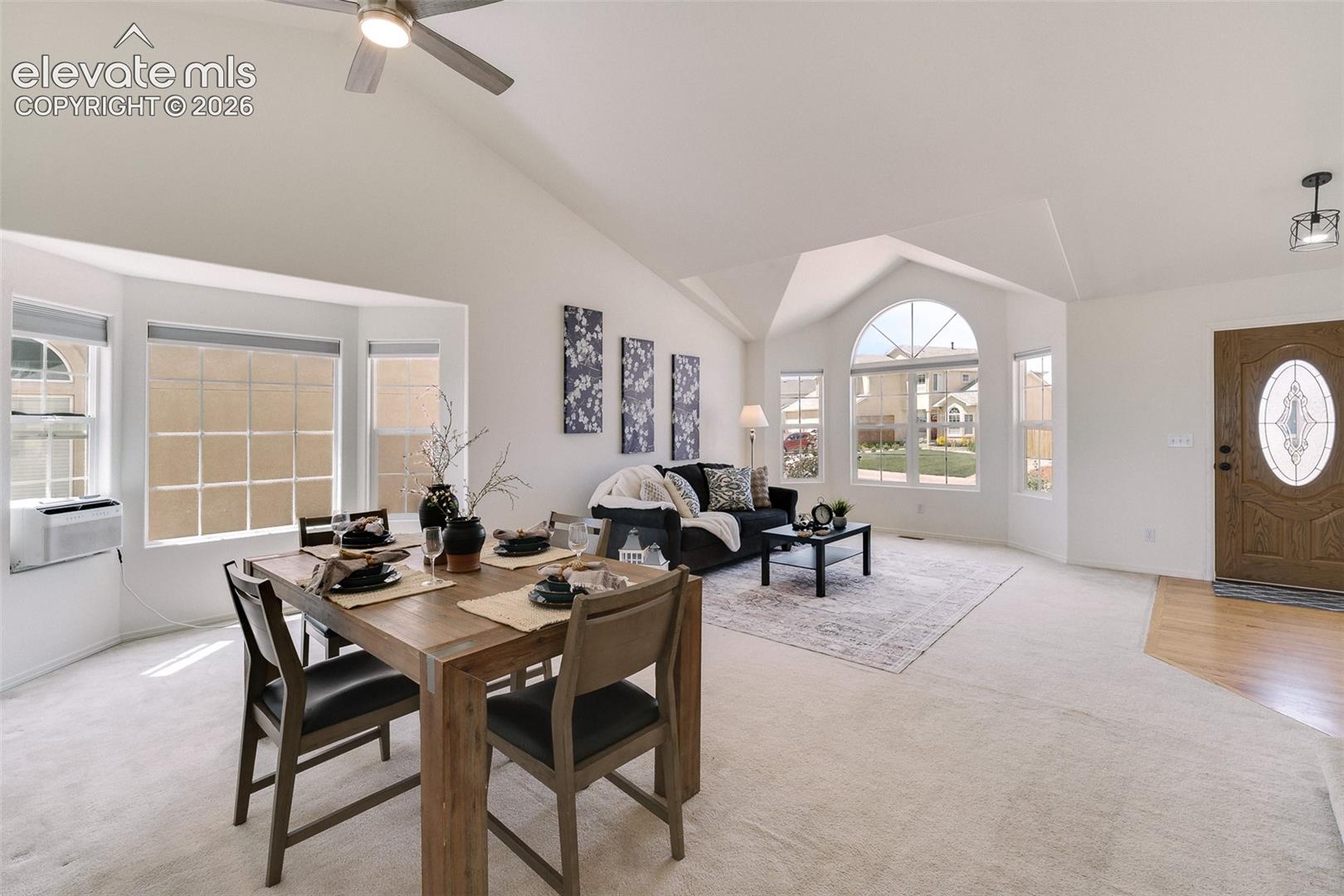 Vaulted ceilings, a decorative arched window, and a paneled entry door with an oval glass insert