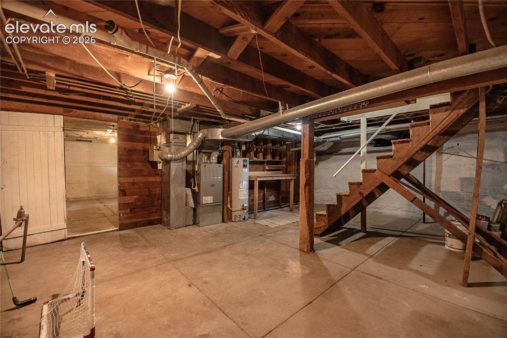 Unfinished basement with concrete flooring and exposed wood ceiling joists