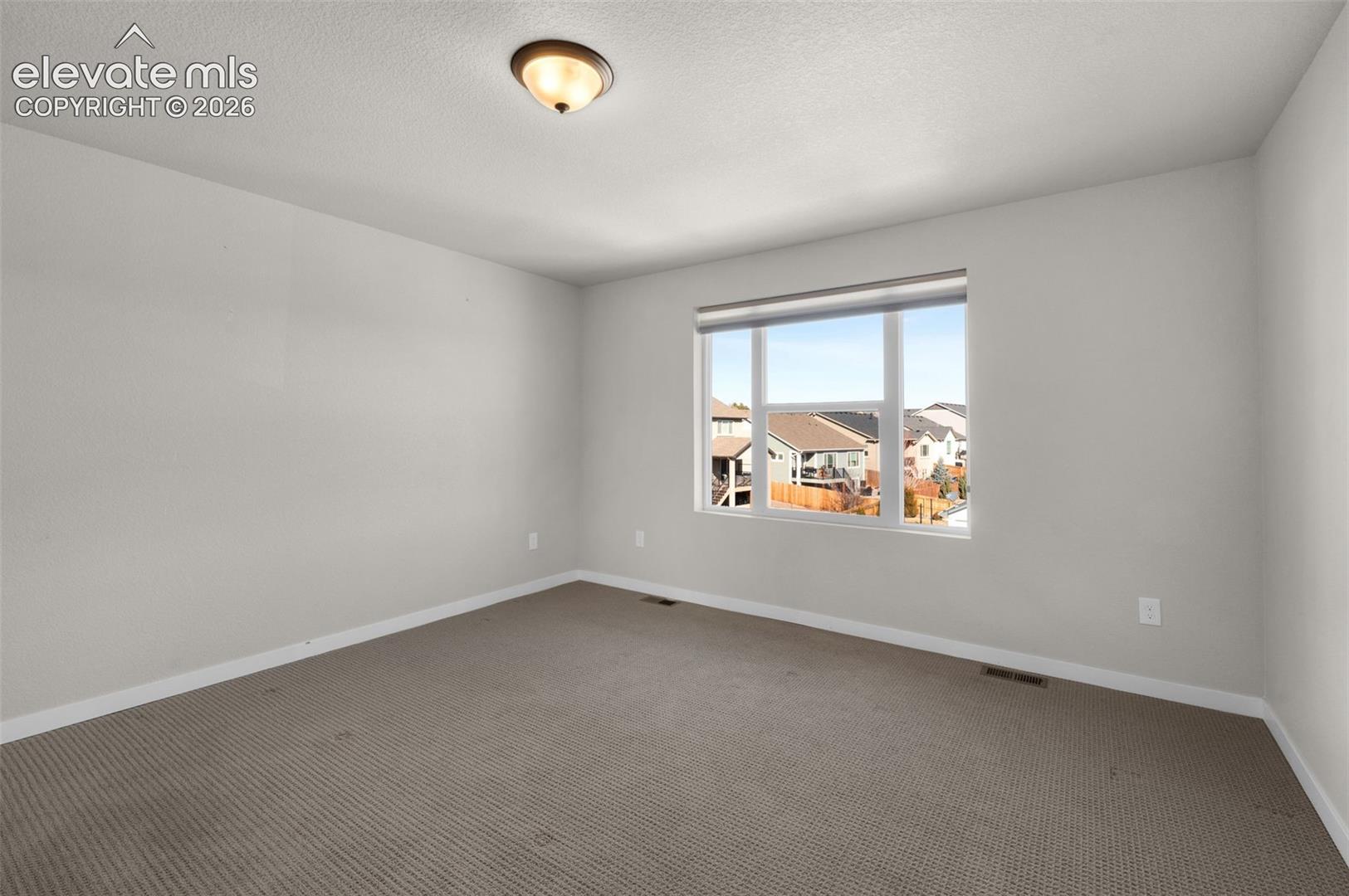 Recessed window offering natural light, textured carpet flooring, and a flush-mount ceiling light