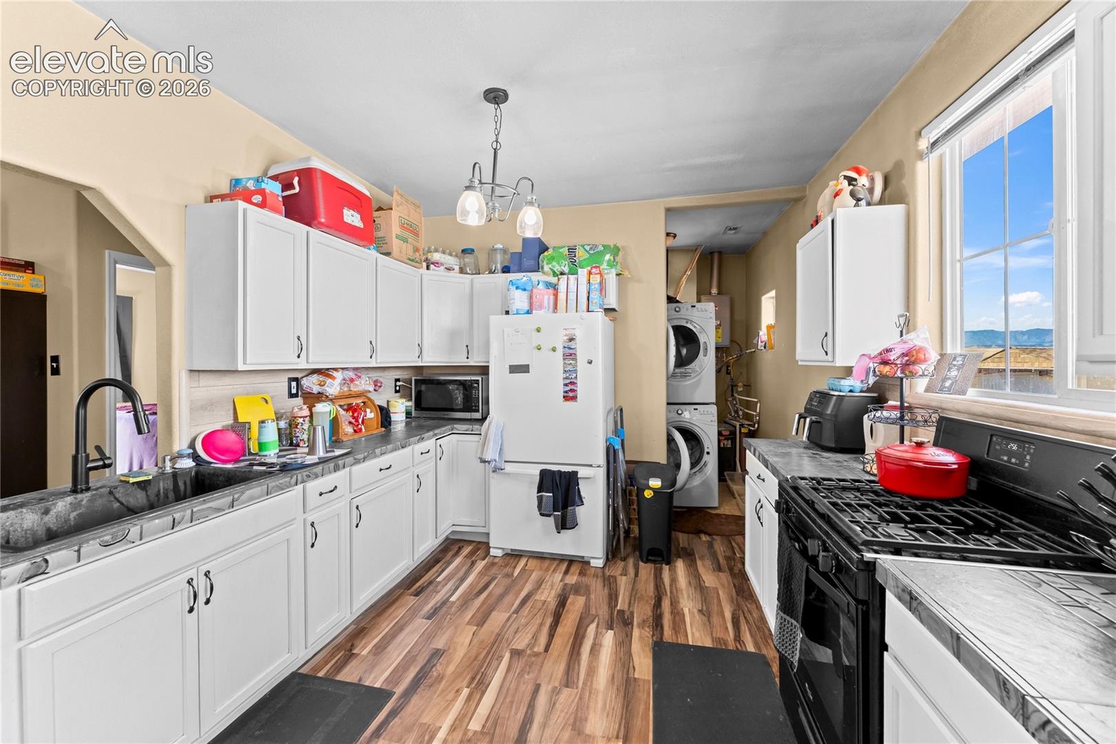 Kitchen featuring white cabinetry, wood-finish flooring, dark-toned countertops, a gooseneck faucet, and a large-pane window