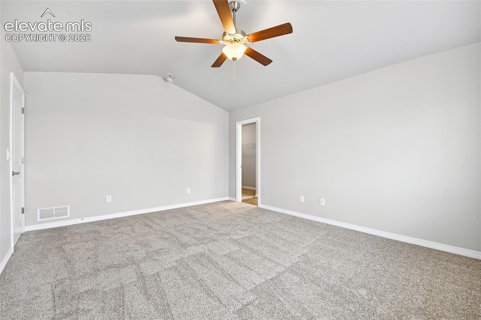 Vaulted ceilings featuring a central five-blade ceiling fan with integrated light fixture and neutral wall-to-wall carpeting