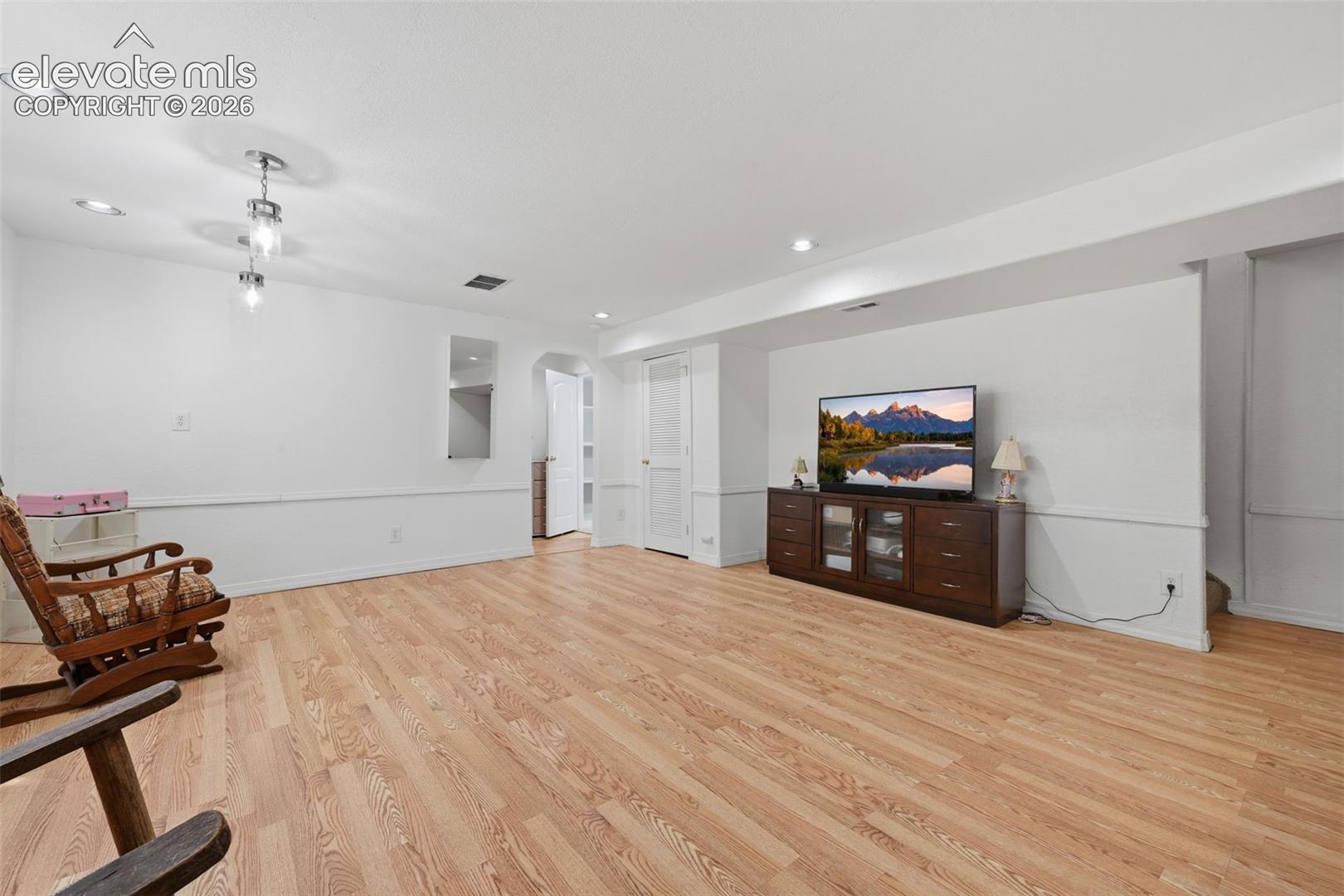 Open-concept living space with wood-finish flooring, recessed lighting, and a built-in wall niche
