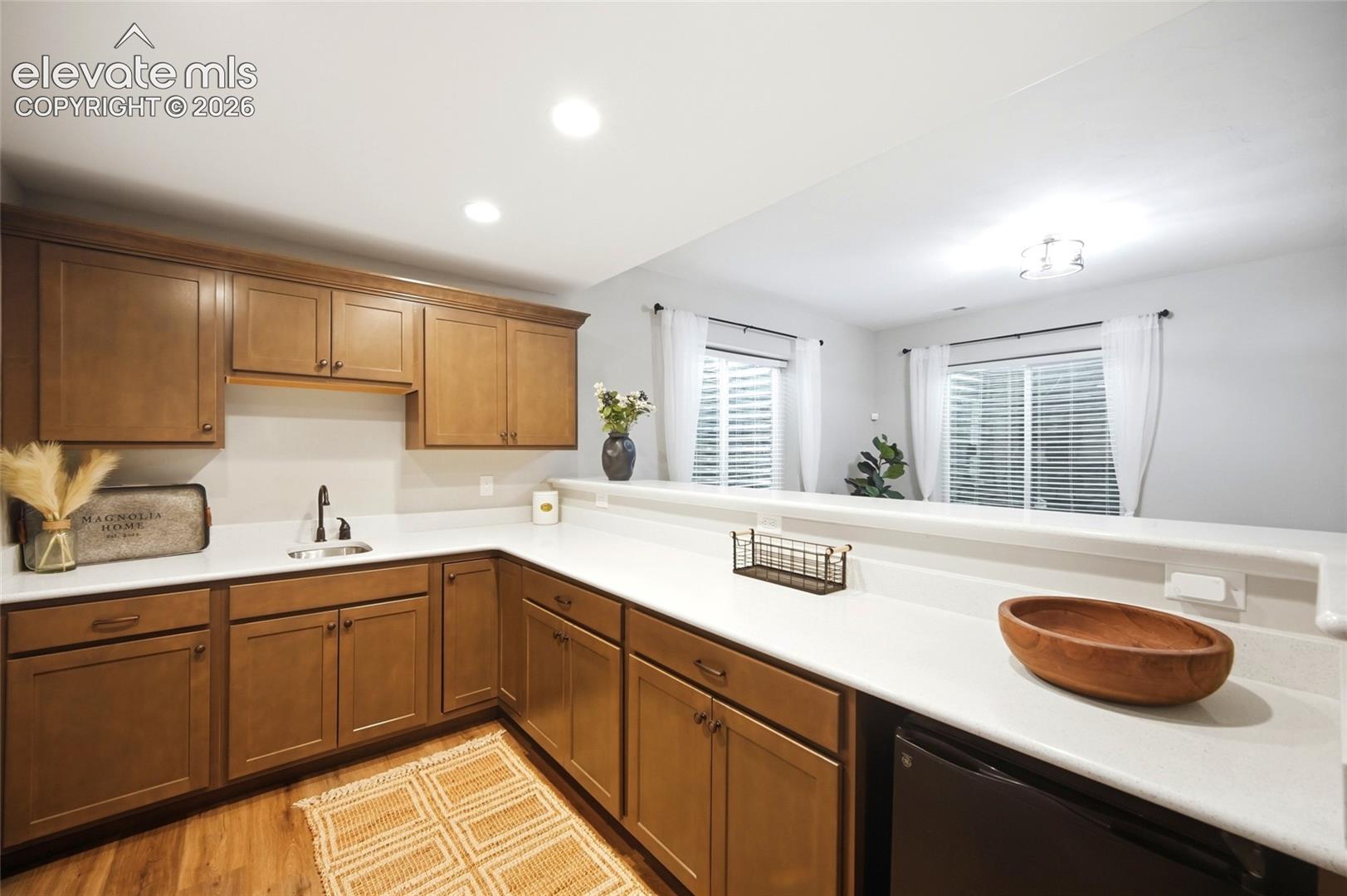 Kitchen featuring medium-toned wood cabinetry, white countertops, recessed lighting, and a dual-basin sink with a matte black faucet