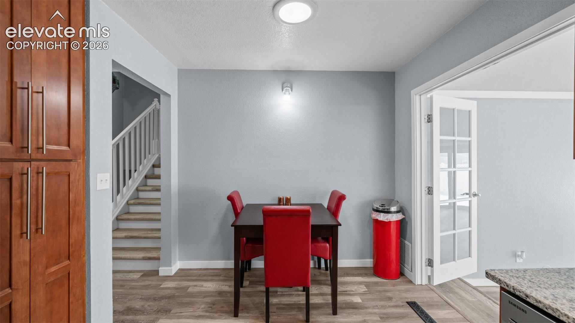 Wood-finish flooring throughout, featuring a light blue wall paint, recessed ceiling lighting, and a white interior door with glass panels