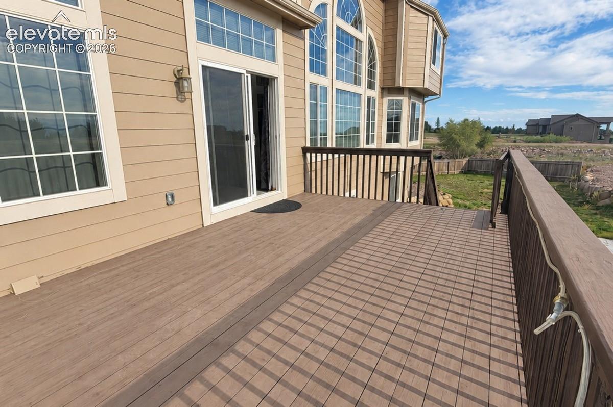 Expansive outdoor deck with decking, a durable railing system, and a sliding glass door entry to the interior