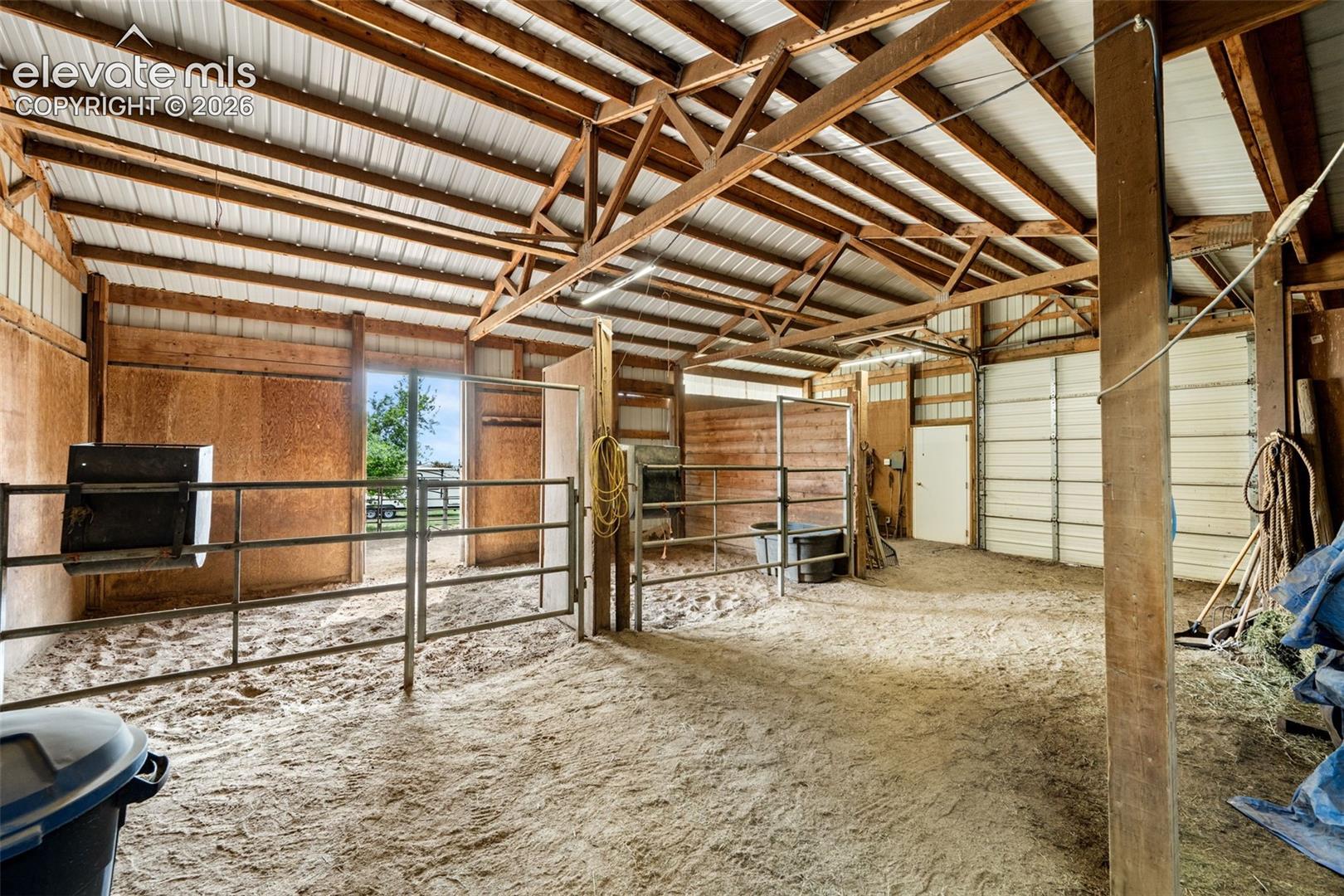 Indoor arena featuring a sand base, exposed wood beams, and a metal roof