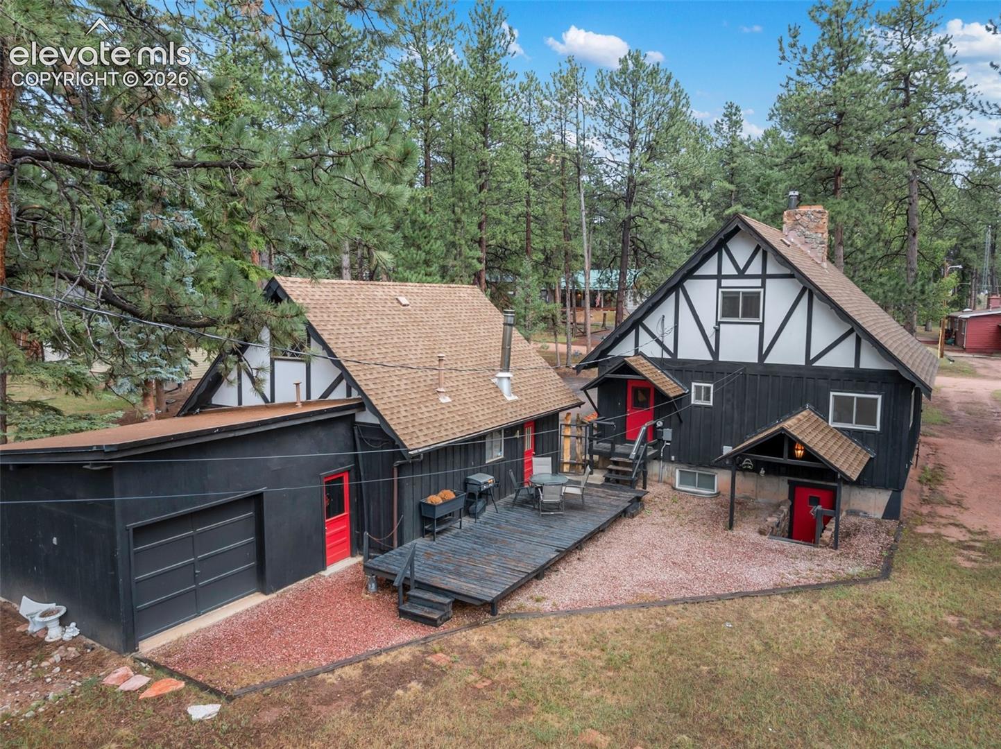 Showing the back of the property, with a deck, separate entrance to the 3rd bay, door entrance to the 2 bay garage, separate door entrance to the main house and separate entrance to the basement.