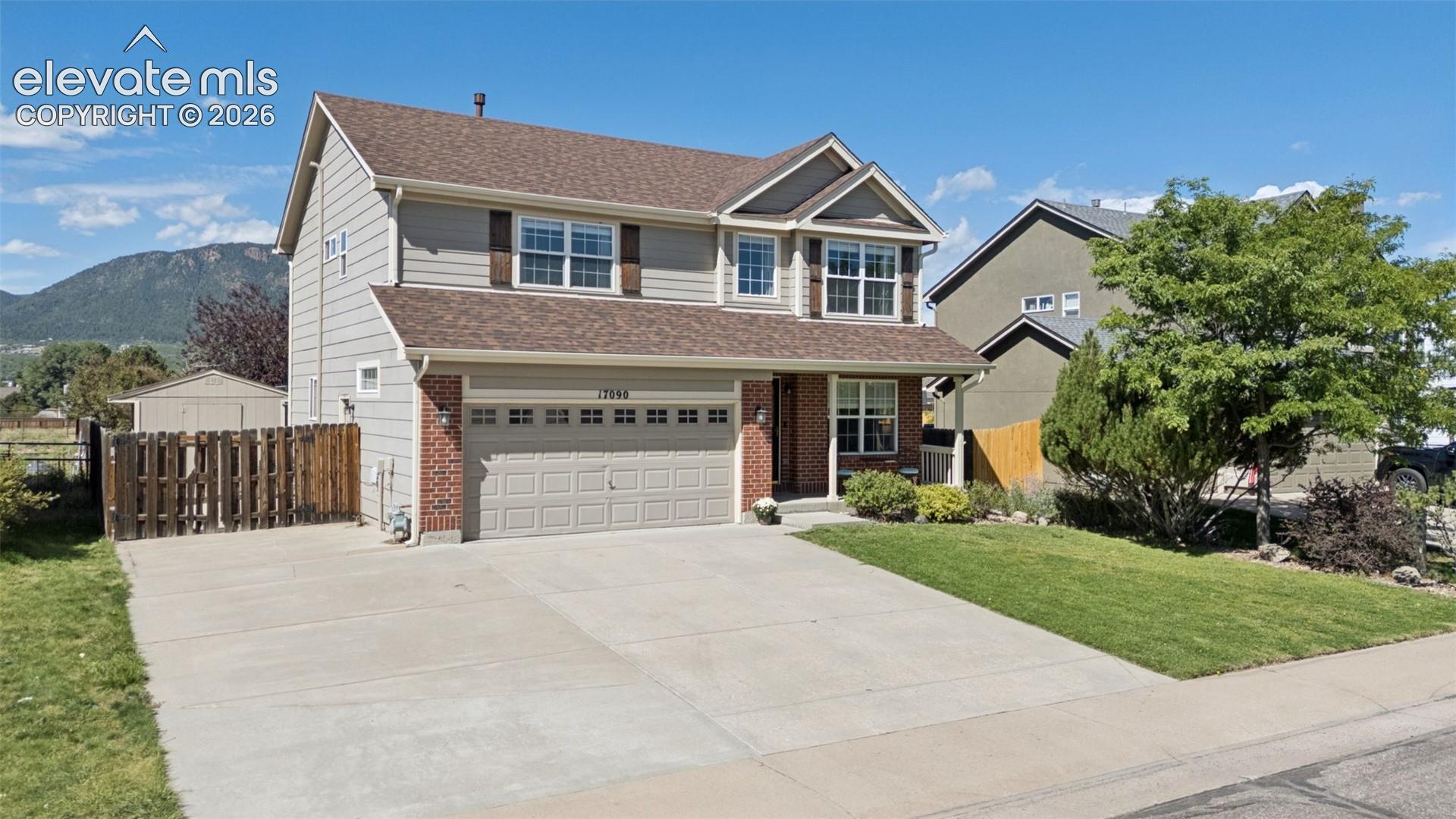 Two-story residence with a two-car garage, brick facade accents, and a concrete driveway