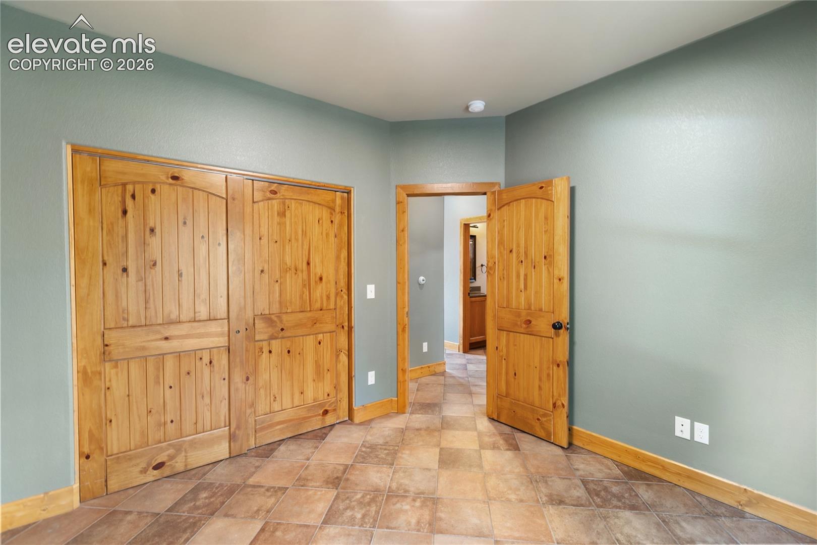 Interior room featuring tile flooring, solid wood doors with arched detailing, and wood trim finishes