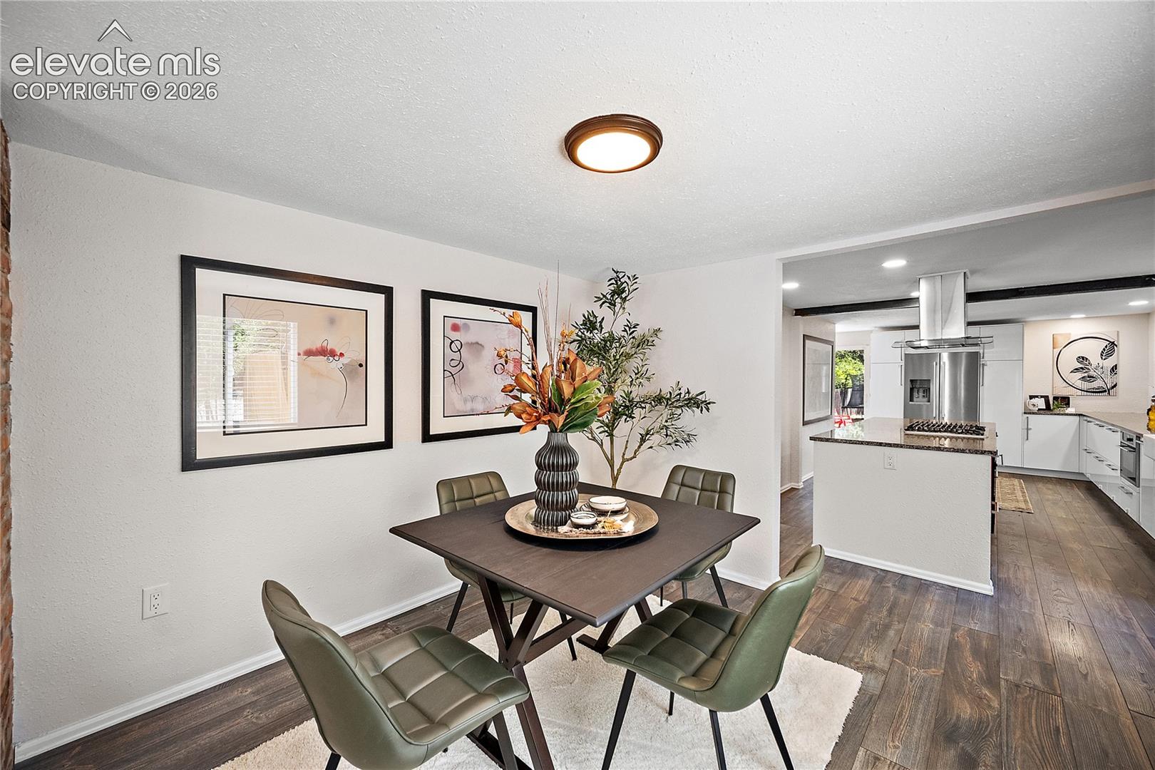 Open-concept dining area with wood-finish flooring, recessed lighting, and a kitchen pass-through