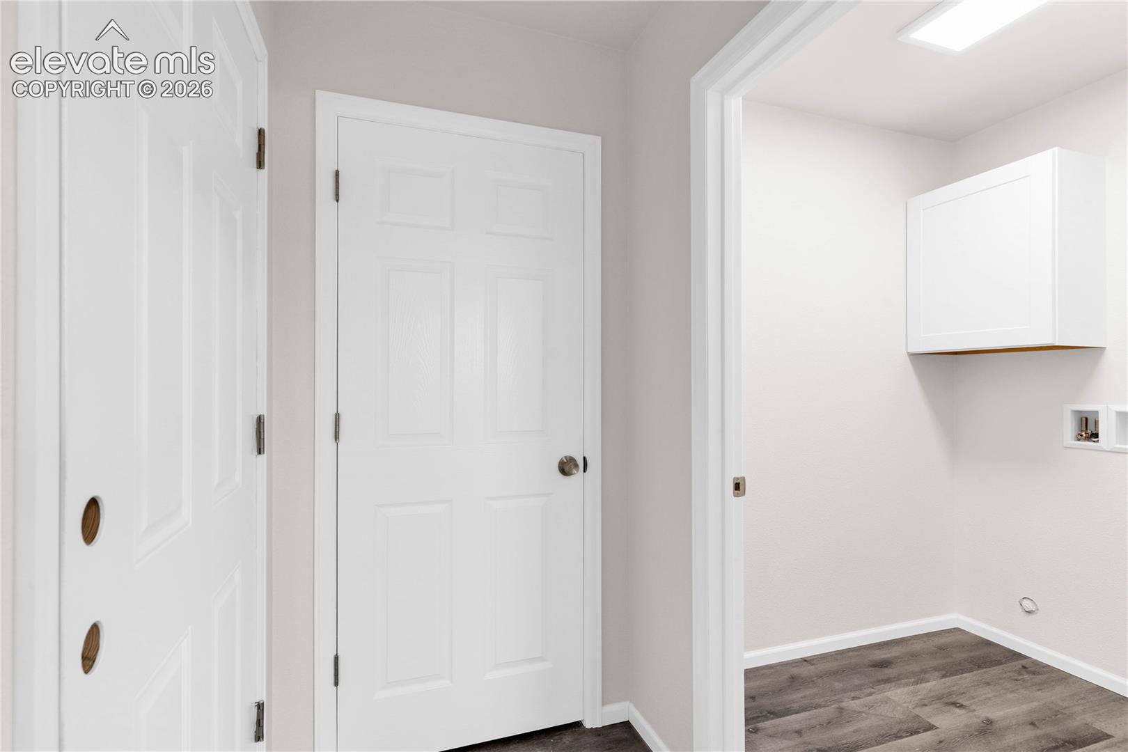 Utility area featuring wood-finish flooring, white shaker-style wall-mounted cabinetry, and recessed lighting