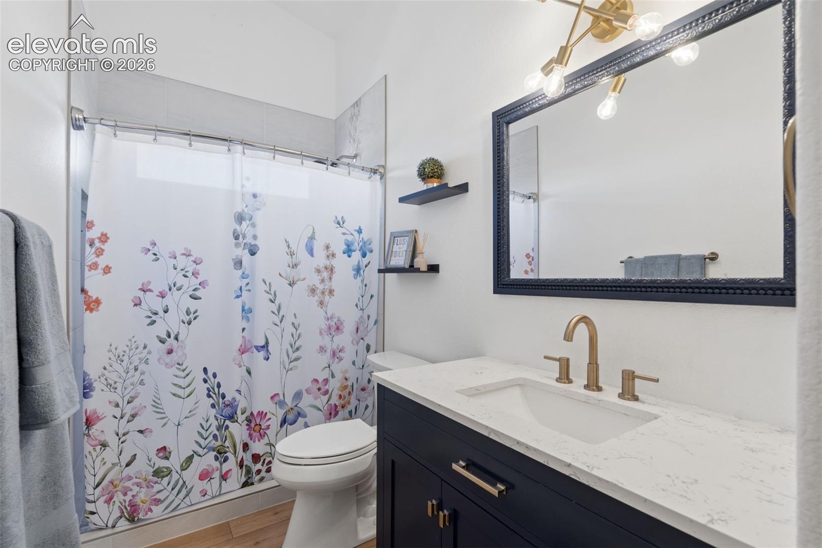Bathroom featuring a vanity with a white countertop, undermount sink, and brass-finish faucet