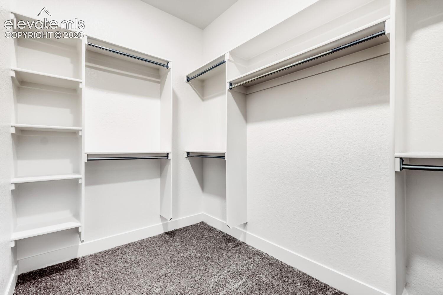 White custom shelving, multiple hanging rods, and textured wall finish