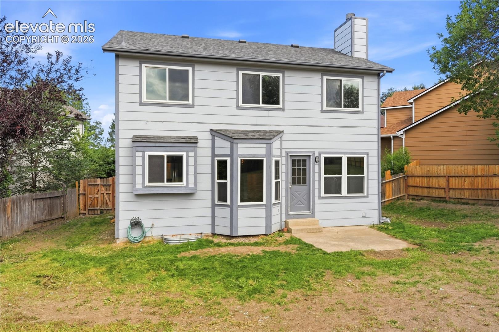 Two-story exterior with horizontal siding, multiple windows, a bay window feature, and a rear entry door