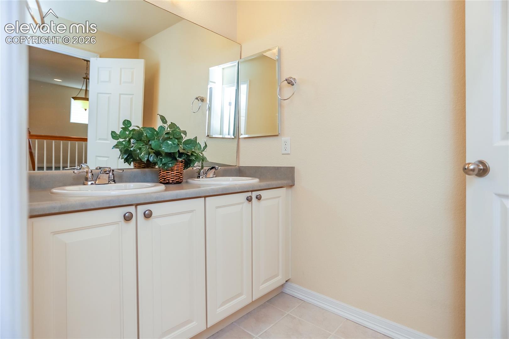 Upper hall bathroom features extended vanity with dual sinks and tile flooring.