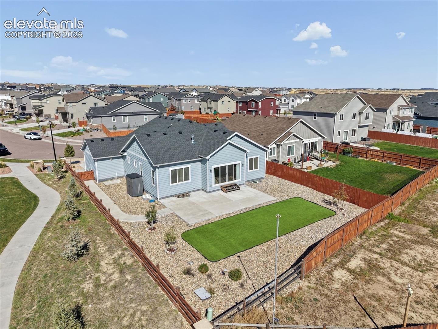 Single-story residence featuring horizontal siding, a composite shingle roof, a rear concrete patio, and a fenced-in yard with artificial turf