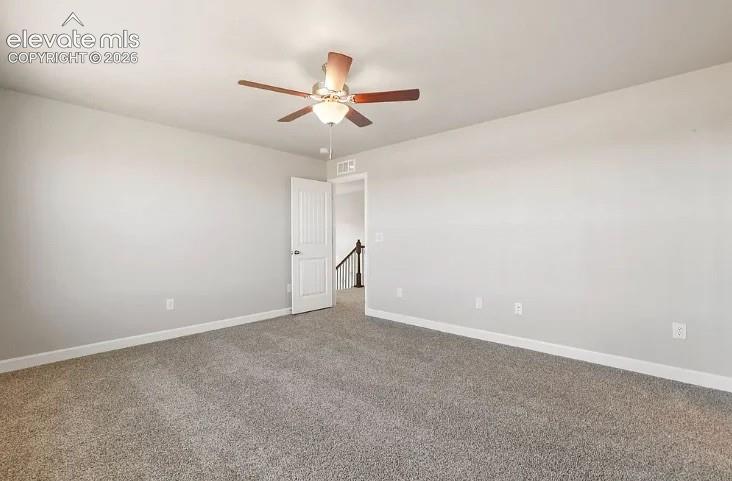 Neutral-toned interior space featuring wall-to-wall carpeting and a ceiling-mounted light fixture with a five-blade fan