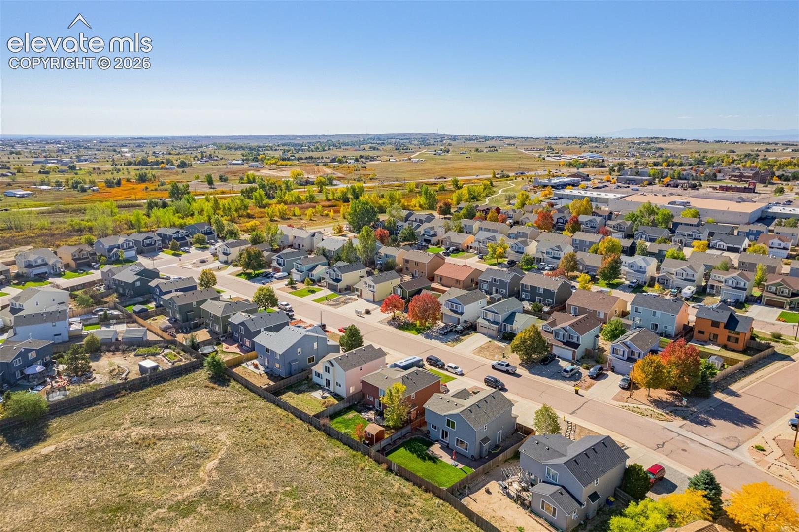 Aerial perspective featuring suburban residential development with surrounding open prairie landscape and paved roadways