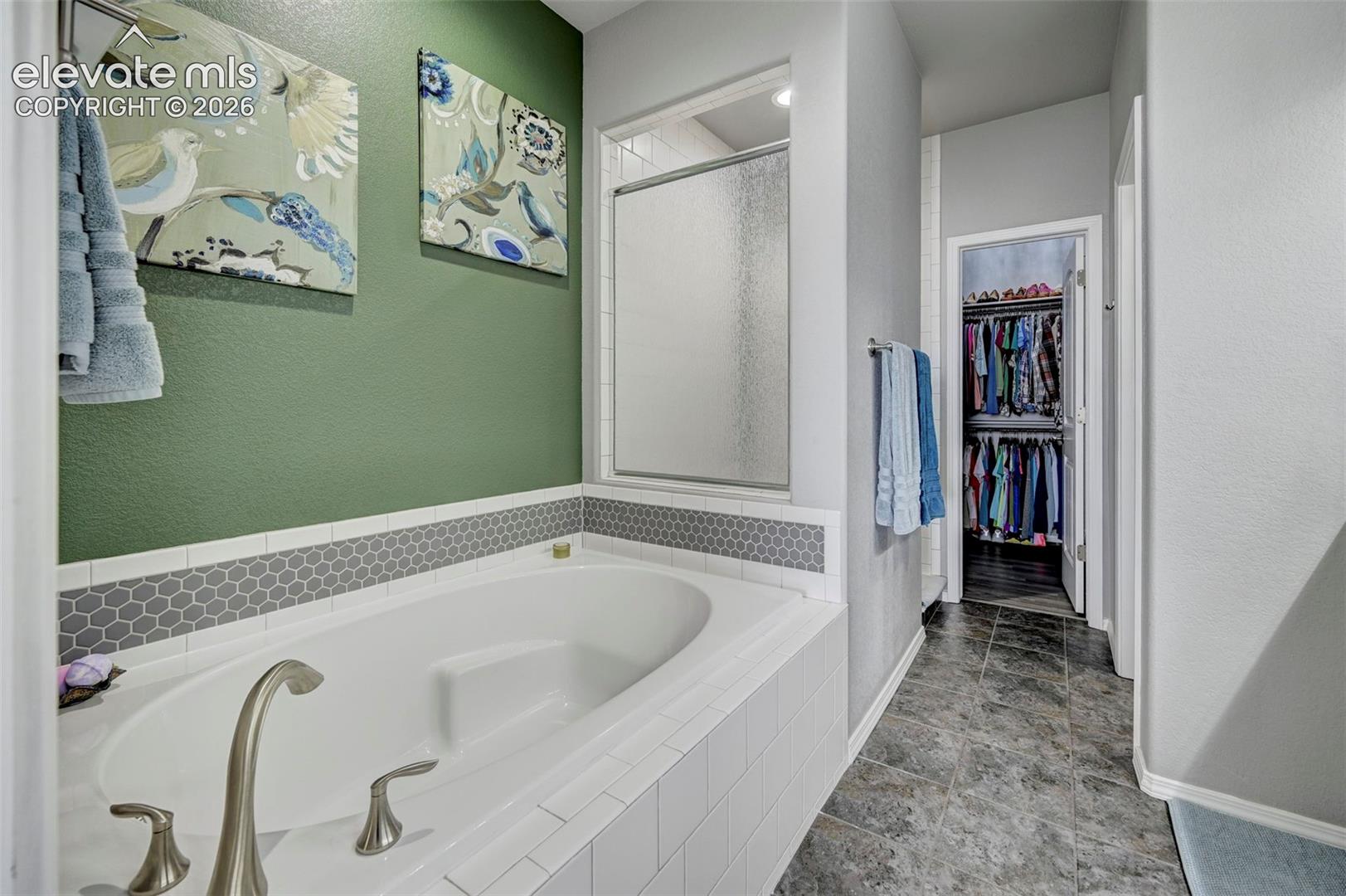 Soaking tub with brushed nickel fixtures and a tiled surround