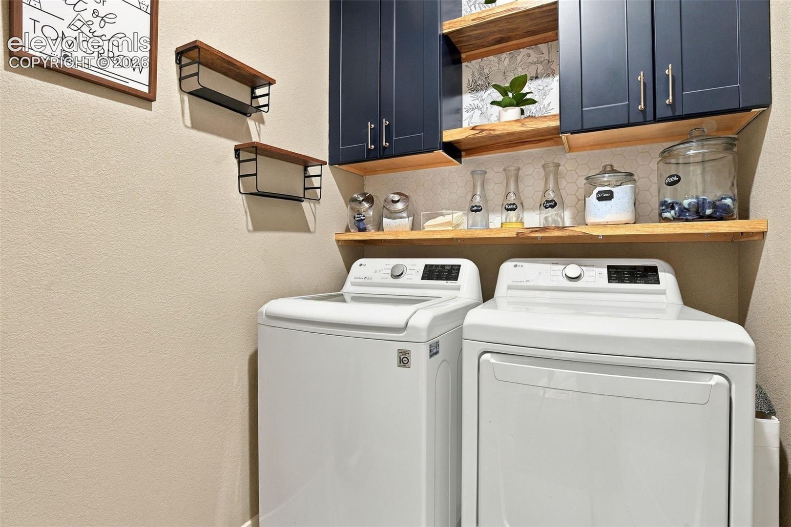 Navy blue shaker-style cabinetry with satin nickel hardware, natural wood open shelving, and a hexagonal tile backsplash