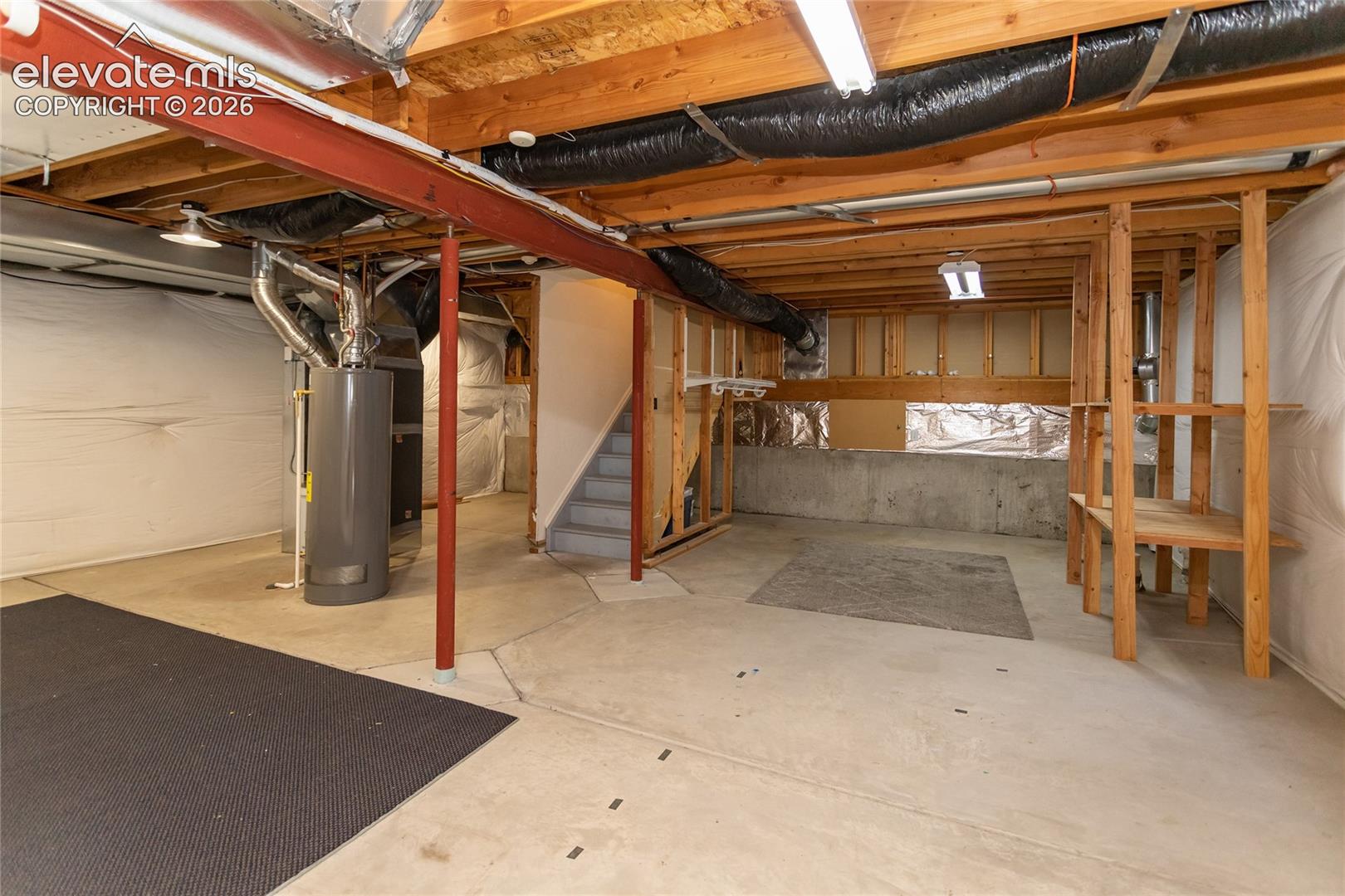 Unfinished basement with a bathroom roughed in.  Featuring built-in wood shelving for storage.