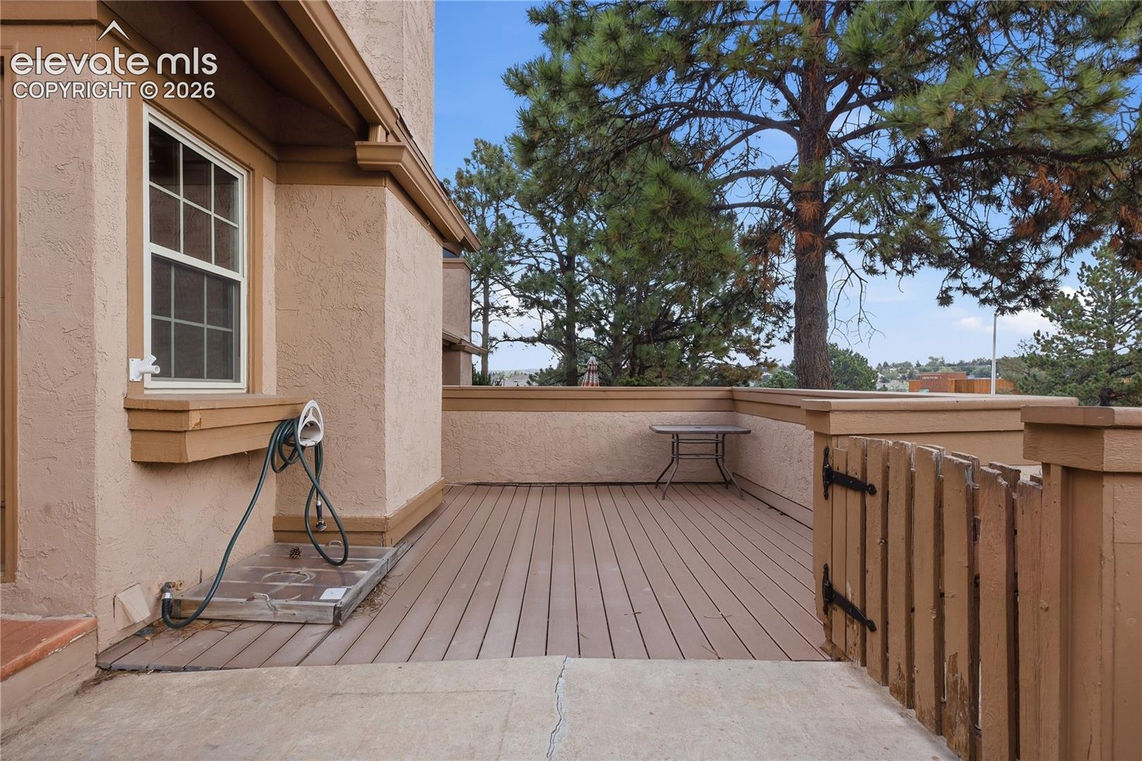 Exterior patio featuring composite decking, stucco siding, and a privacy fence