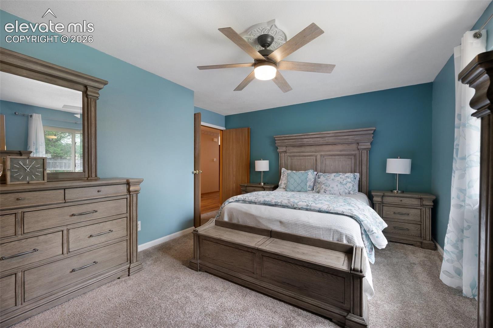 Carpeted bedroom with a ceiling fan and baseboards