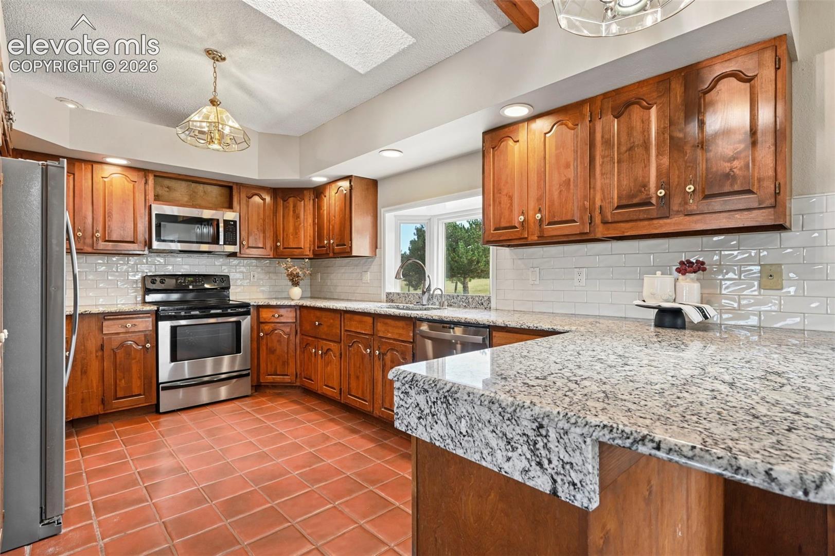 Kitchen featuring Granite Counters, Stainless Appliances, Wood Cabinets.