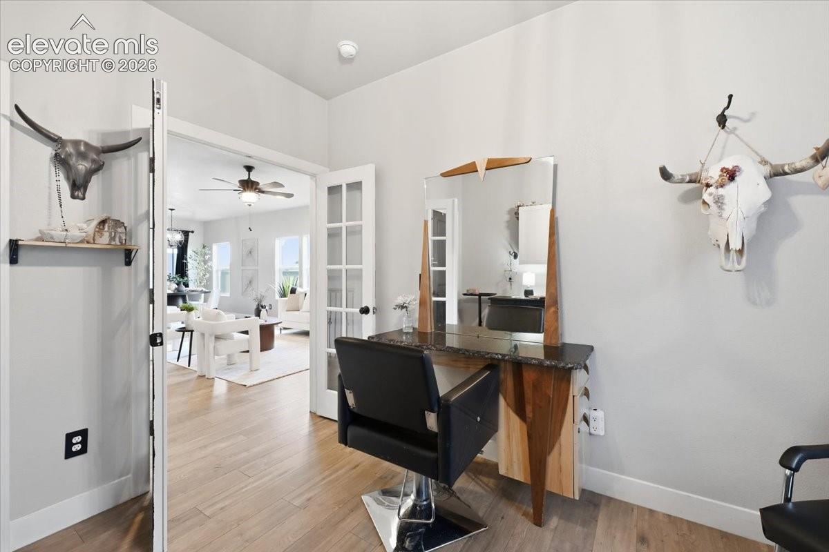 Wood-finish flooring throughout, French doors, and a ceiling fan in the adjacent space