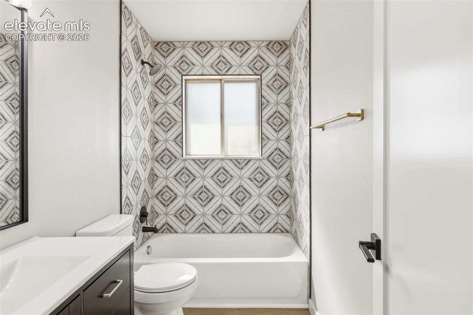 Bathroom featuring a white bathtub with a tile surround and a vanity with a white countertop