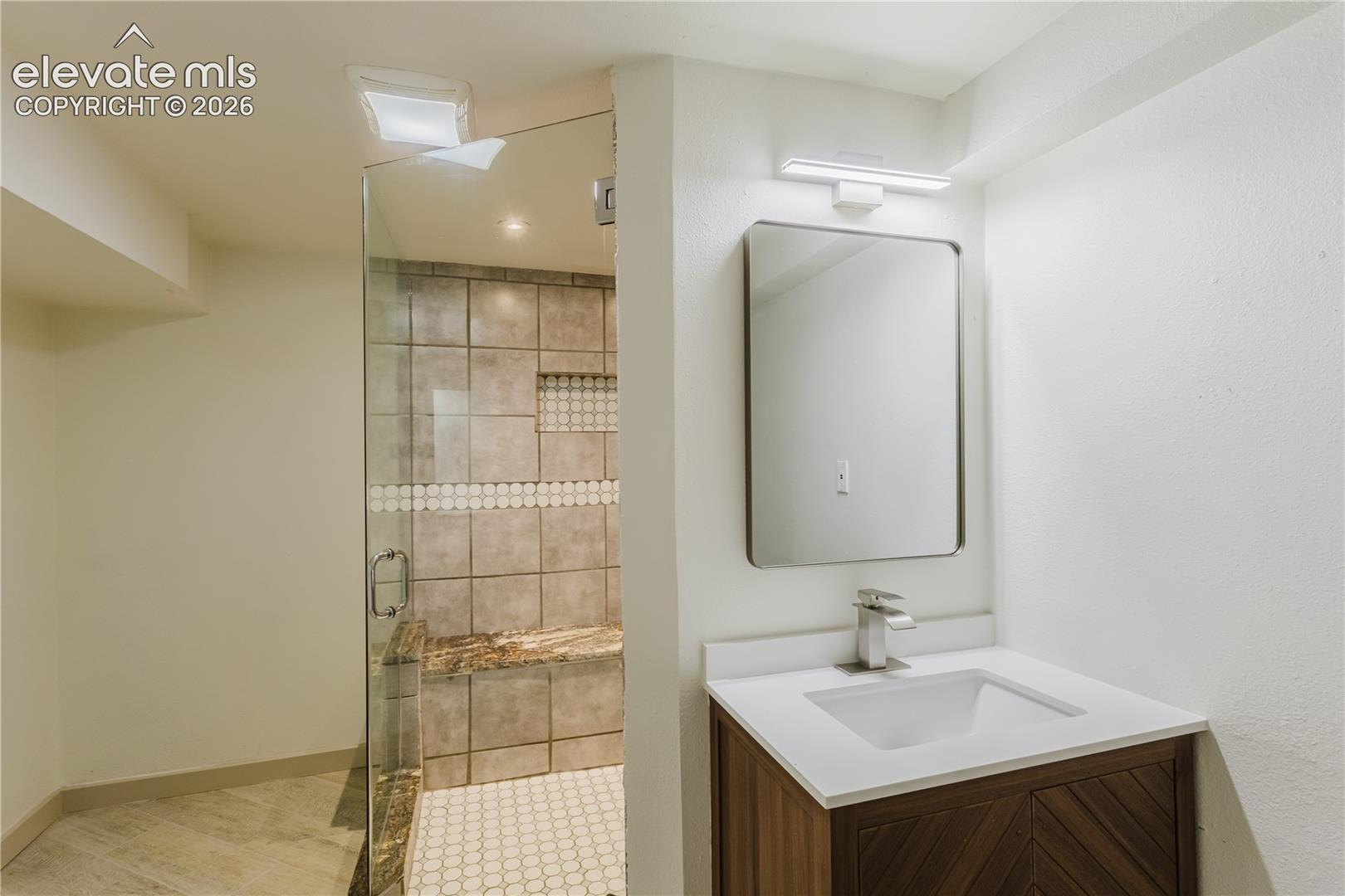 Contemporary bathroom featuring a walk-in shower with glass enclosure, mosaic tile accents, a built-in stone bench, and hexagonal floor tiles