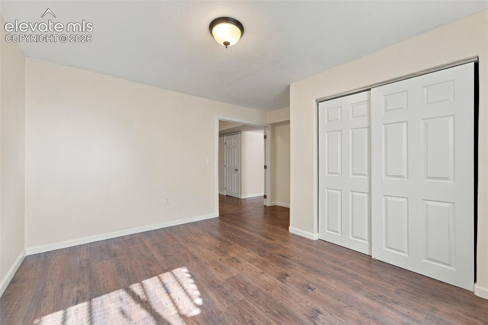 Wood-finish flooring, neutral wall tones, semi-flush mount lighting, and a closet featuring six-panel sliding doors