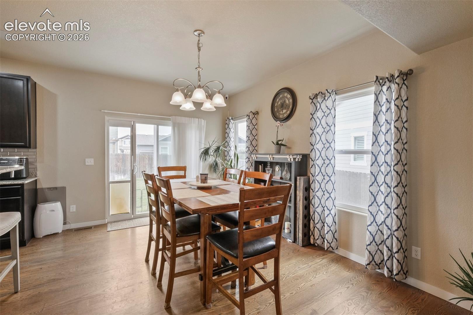 Dining area with wood-finish flooring and a contemporary chandelier