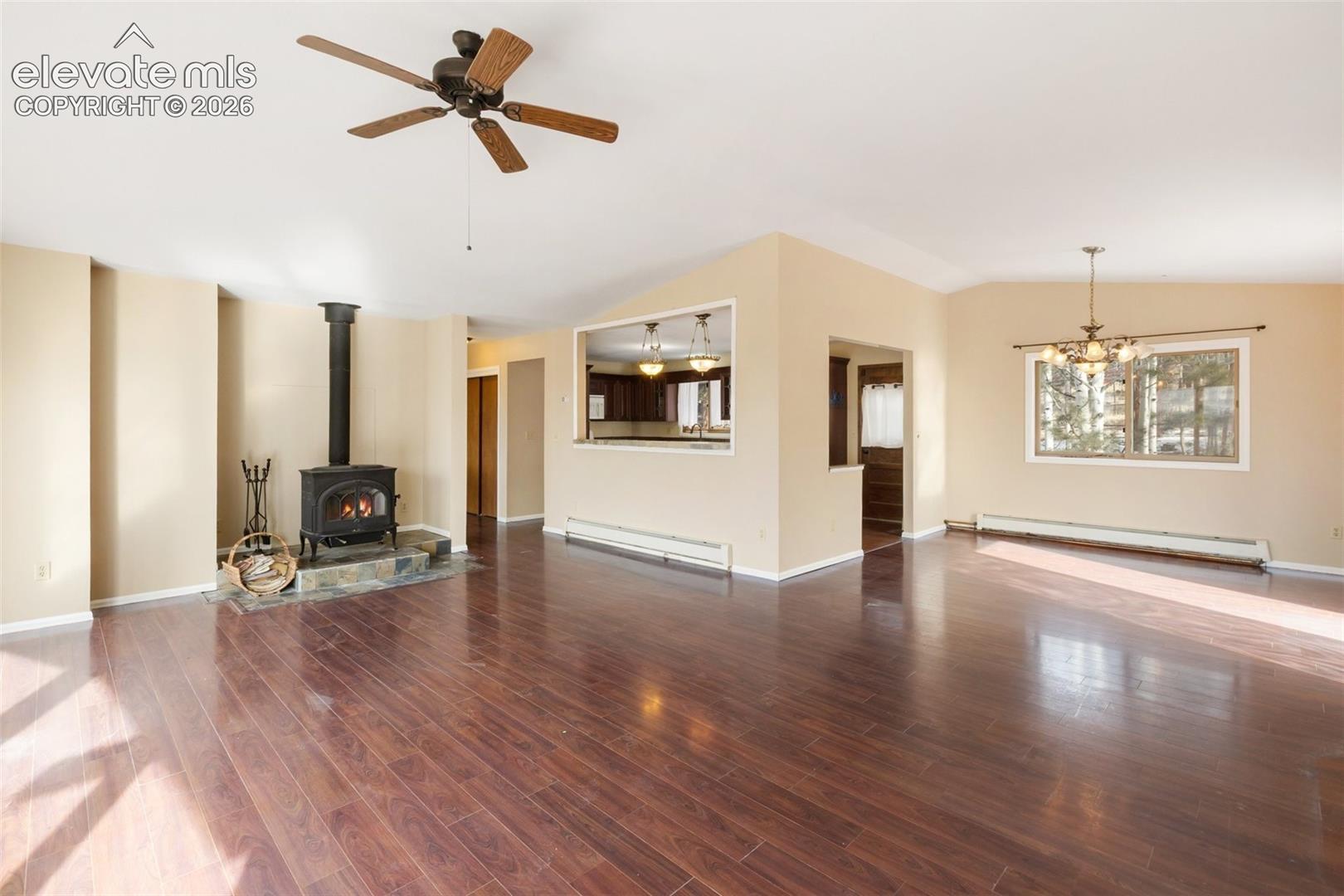 Hardwood-style flooring, a wood-burning stove on a stone hearth, and an open pass-through to an adjacent space