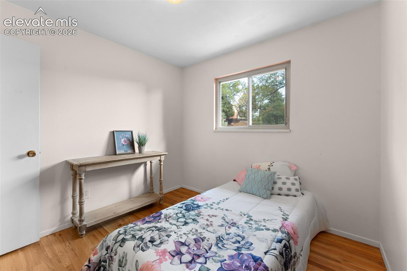 Hardwood-style flooring with light wall tones, a white door, and a built-in window