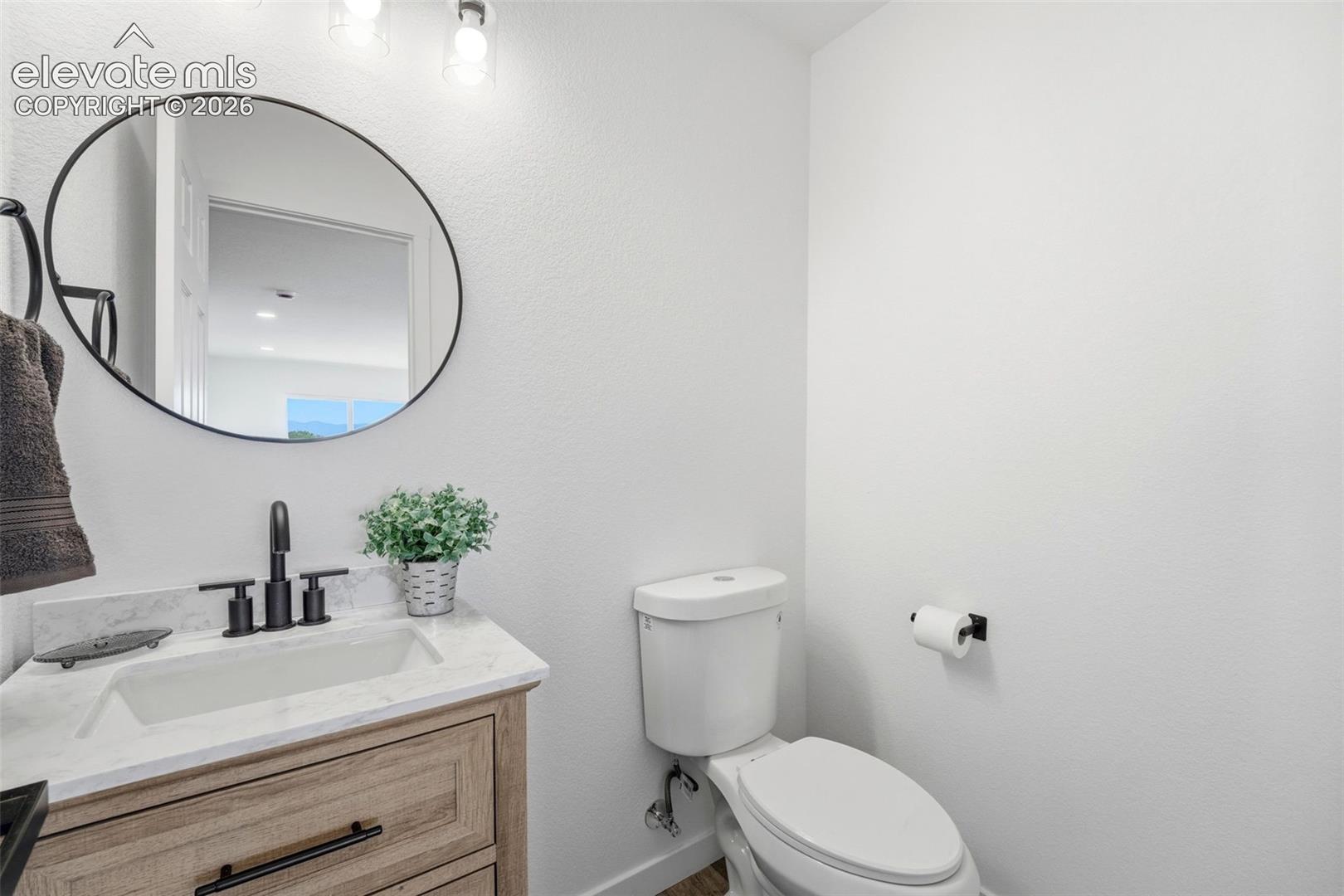Modern bathroom featuring a wood-finish vanity with a white countertop and integrated sink