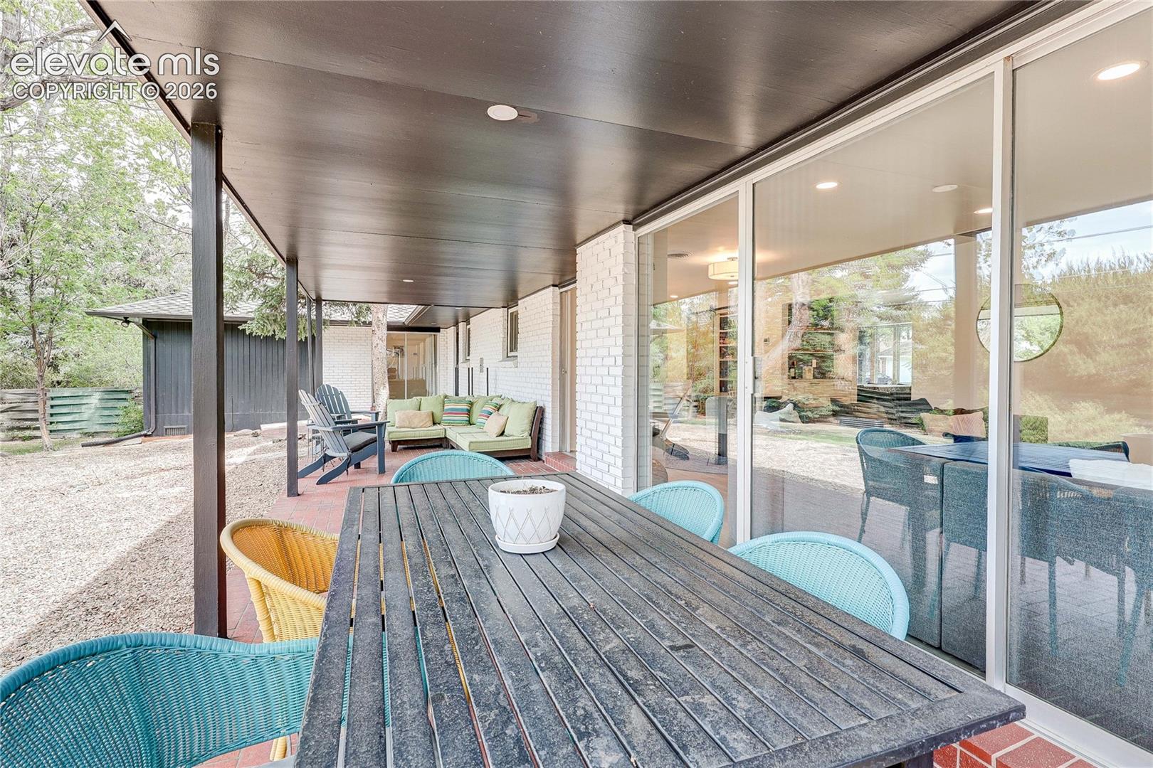 Covered patio with brick flooring, recessed lighting, white brick exterior, and large sliding glass doors