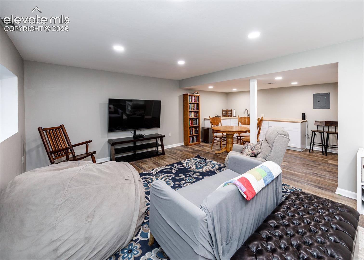 Spacious recreational area featuring wood-finish flooring, recessed lighting, and a built-in wet bar with white cabinetry and wood countertops