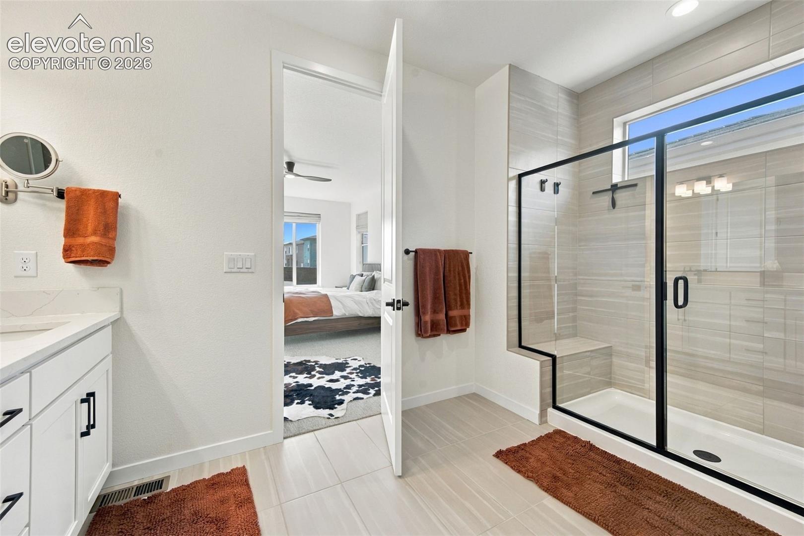 Bathroom featuring a white vanity with hardware, a walk-in shower with horizontal wall tile, a built-in shower bench, and a framed glass enclosure