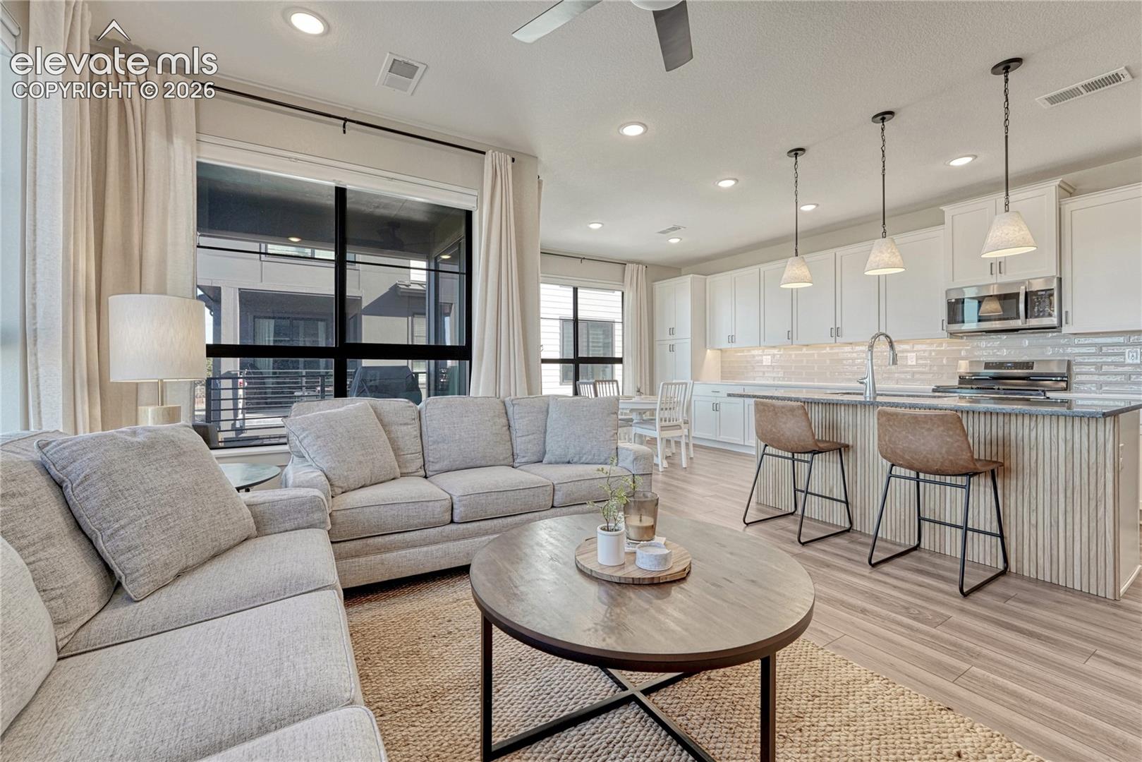 Kitchen featuring white shaker cabinetry, tiled backsplash, recessed lighting, and a kitchen island with a slatted base and integrated countertop