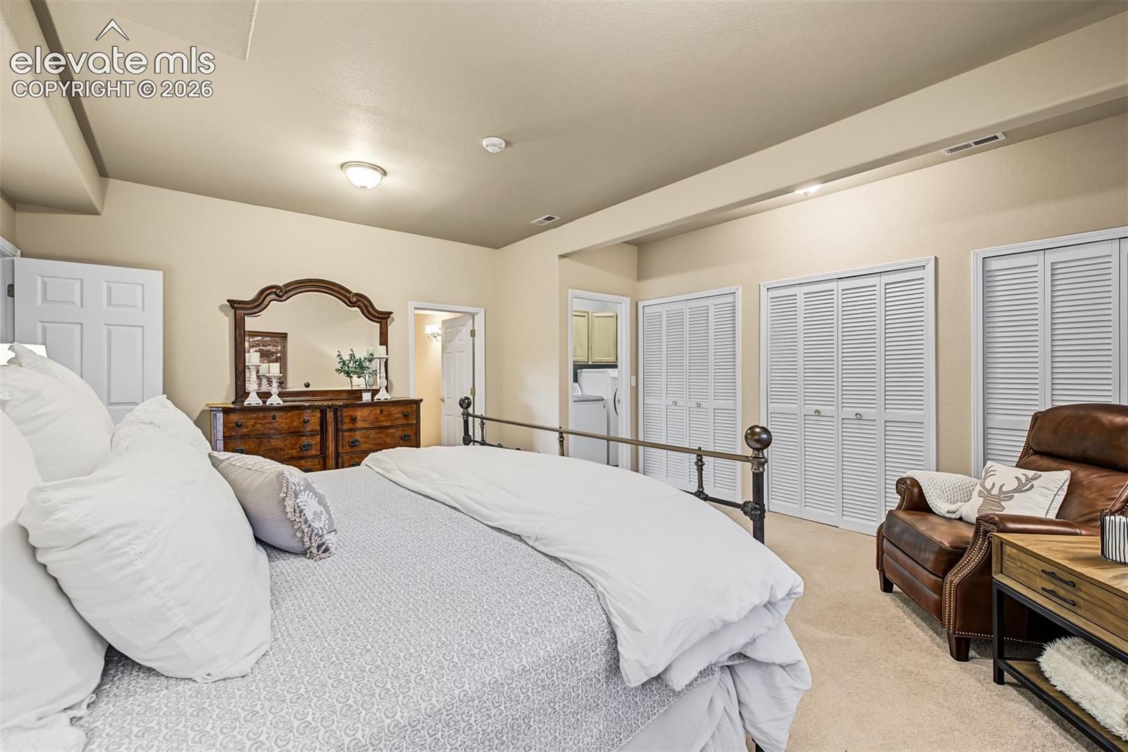 Additional view of the spacious walkout basement bedroom suite, highlighting generous closet space, a sitting area, and separate access to the full bathroom with shower and laundry room.