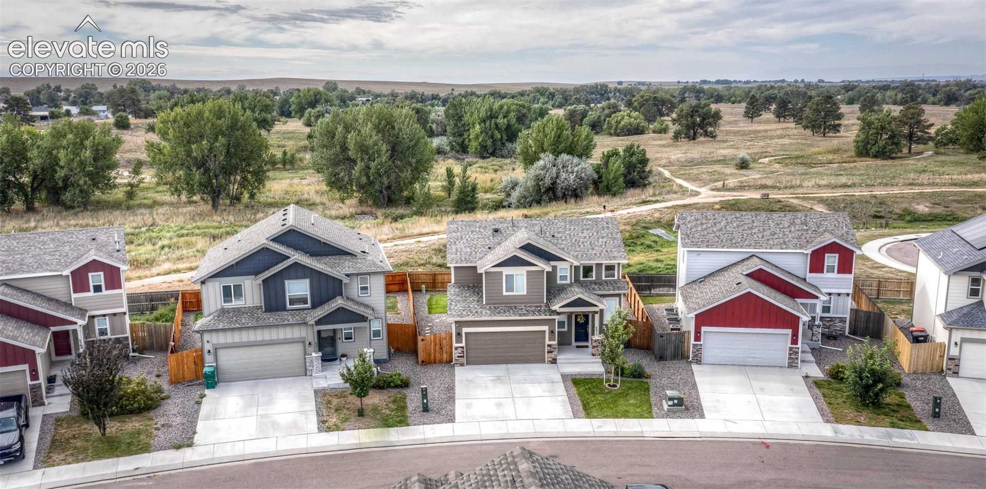 Aerial perspective of suburban residences featuring multi-pitched rooflines, integrated two-car garages, mixed-material siding, and concrete driveways