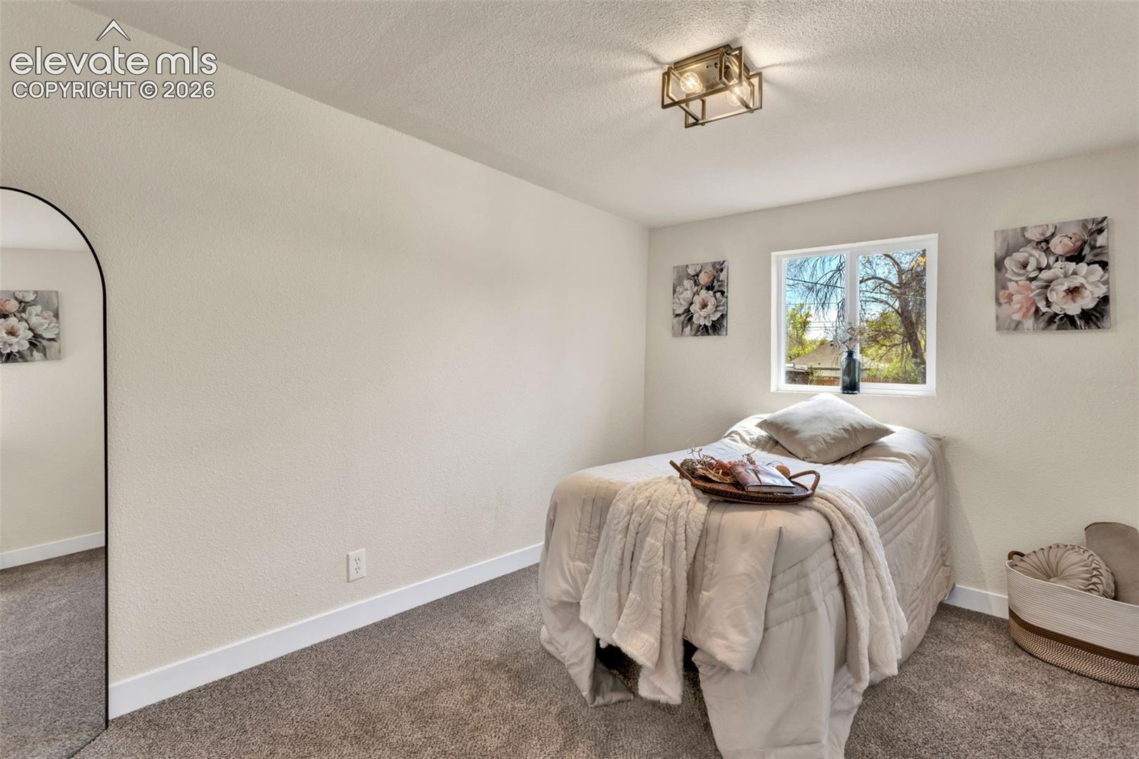 Room featuring textured walls, a single window, and a flush-mount light fixture