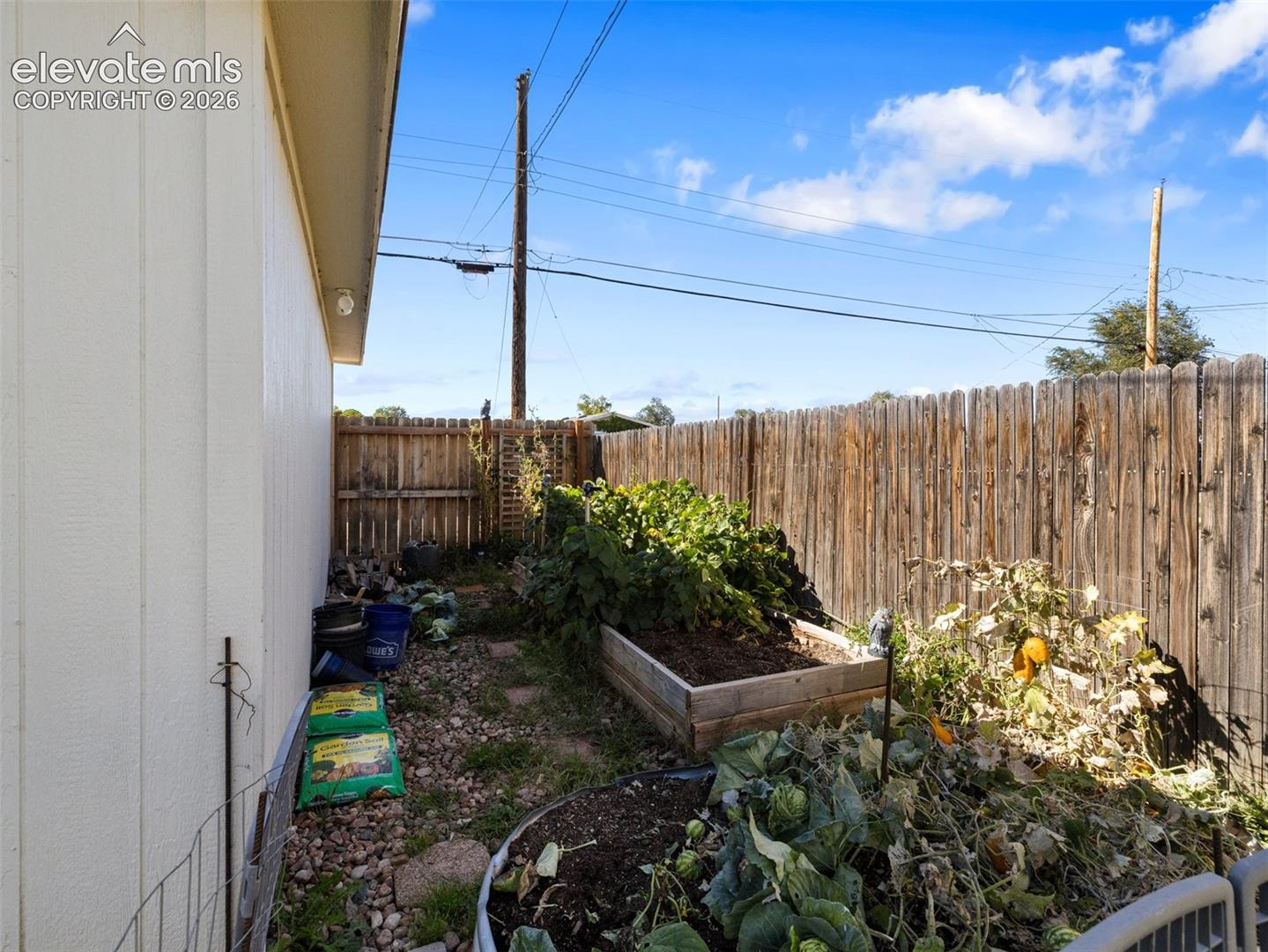 Private fenced yard featuring a raised garden bed and vertical wood fencing