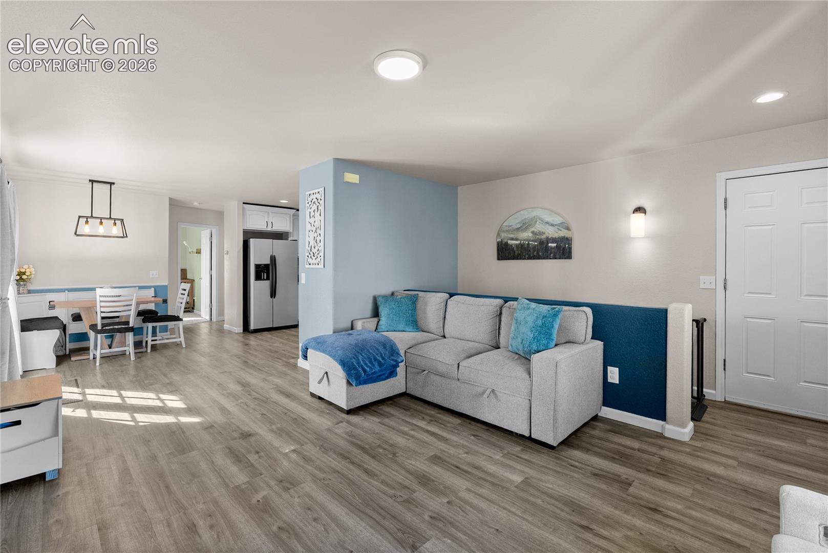Wood-finish flooring throughout, recessed ceiling lighting, and a modern rectangular chandelier