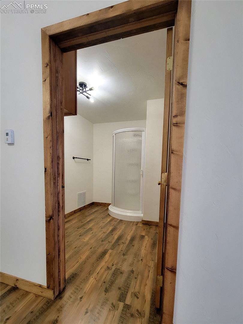 The bathroom features laminate wood flooring with a corner shower enclosure