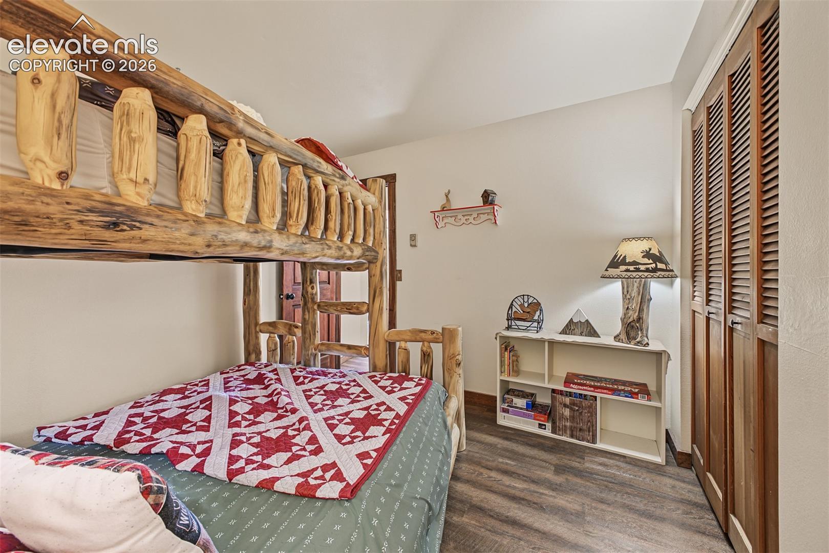 Bunk bed with natural wood frame, wood-finish flooring, built-in shelving, and louvered bi-fold closet doors